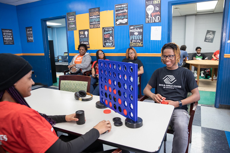 Club teens sitting inside playing Connect 4